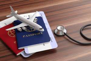a toy airplane on passports beside a stethoscope to illustrate travel insurance for digital nomads