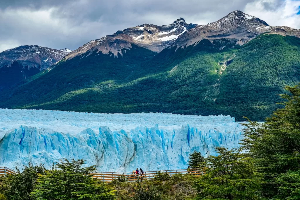 a glacier with trees and mountains in the background