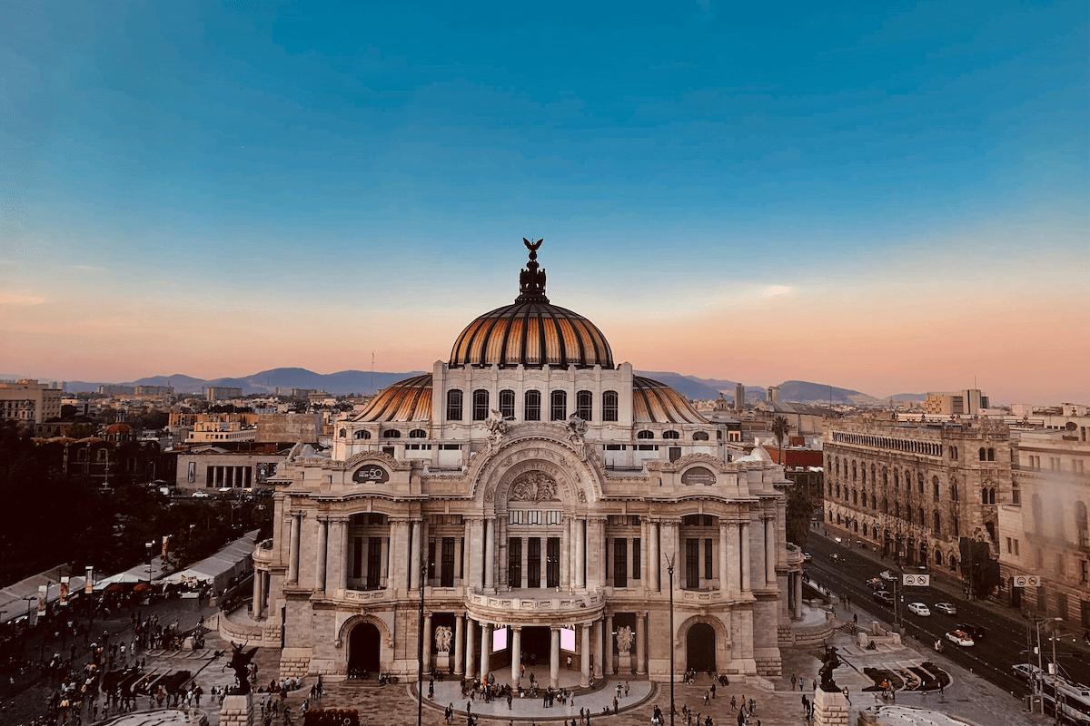a large building with a dome and people walking around in Mexico City