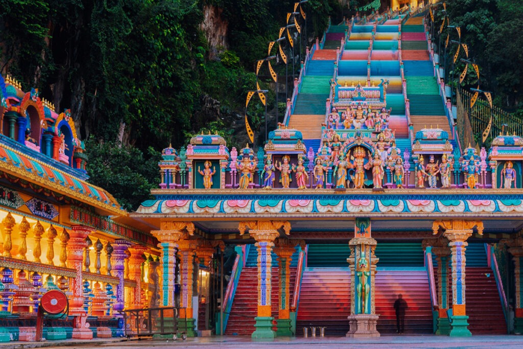 a multi-colored religious building with pillars and steps at Batu Caves Malaysia