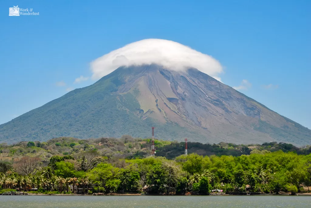 off-the-beaten-path-destinations-ometepe-nicaragua a volcano along a jungle river with a cloud over it in Ometepe Nicaragua