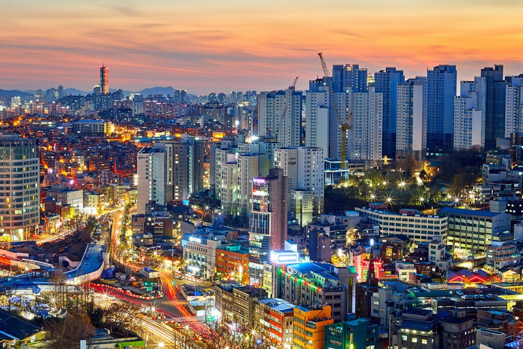 a city with many tall buildings at dusk with lights turning on